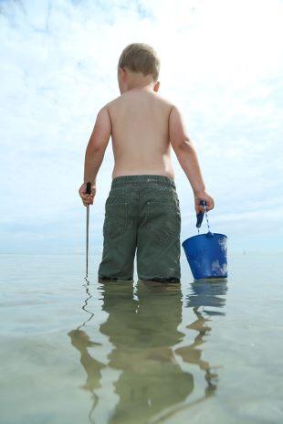 Junge spielt im Wasser mit Scrunch Eimer
