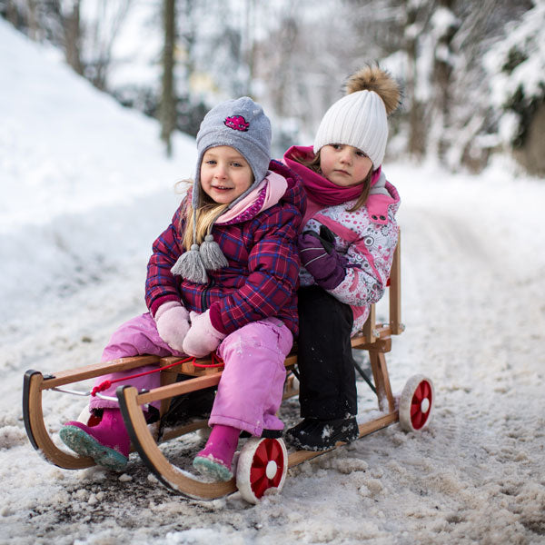2 Kinder sitzend auf einem Holzschlitten mit Rollen Roll Rodel Mami Poppins