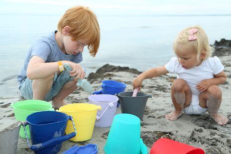 Kinder spielen am Strand mit Scrunch Eimer diverse Farben